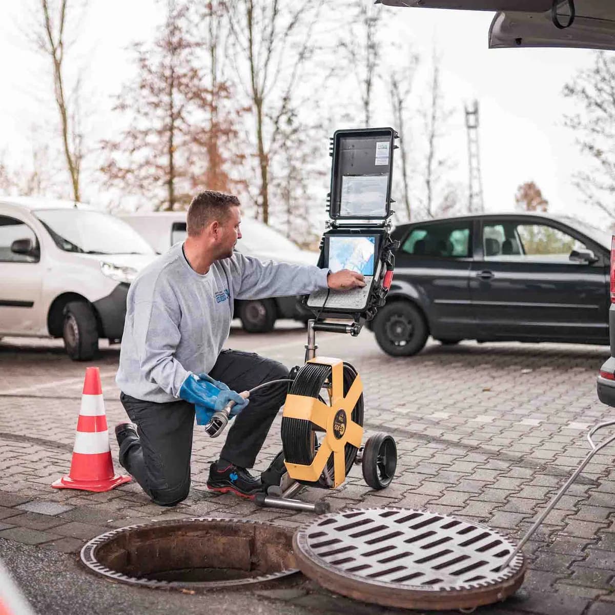 Techniker reinigt Kanal per Hochdruckspülung am Haus